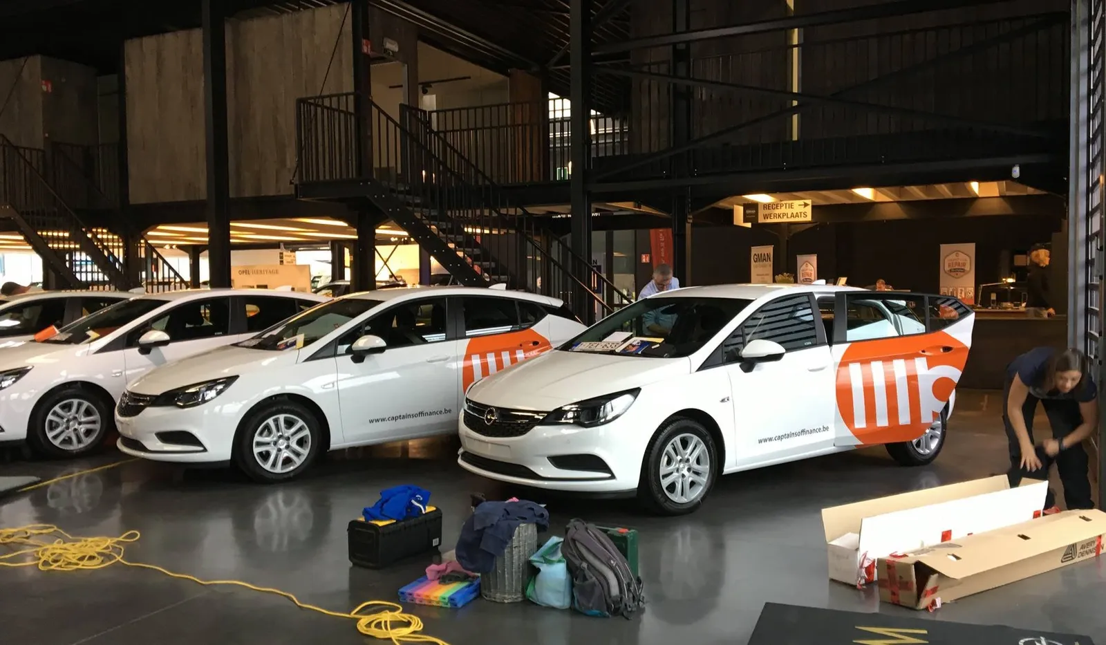 Drie witte vloot-wagens krijgen identieke huisstijlbelettering op locatie in de garage